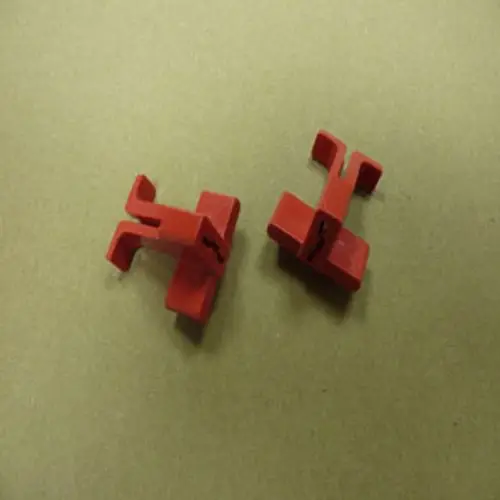 Zwei rote Clips für Abgasrohre von Remeha auf einer neutralen Unterlage, in einfacher Form für die Montage.